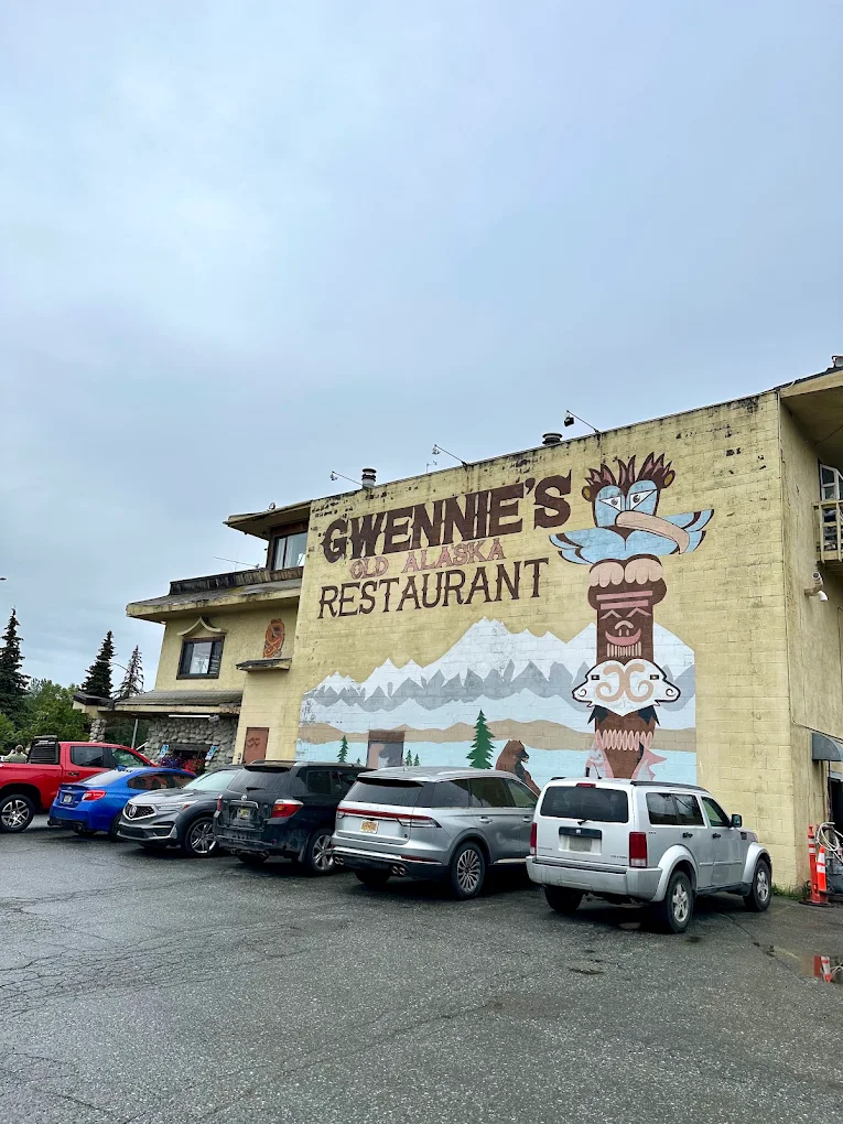 Painted mural on the exterior wall of Gwennie's — mountains, totem, and hand-lettered sign